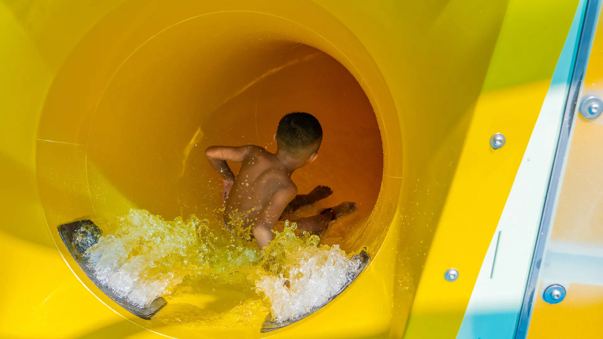 Child sliding down a yellow enclosed tube slide at Waterbom Bali